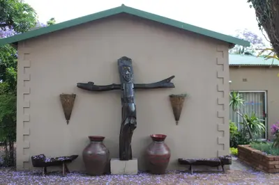 a statue of a cross in front of a building at African Roots Guest House in Polokwane