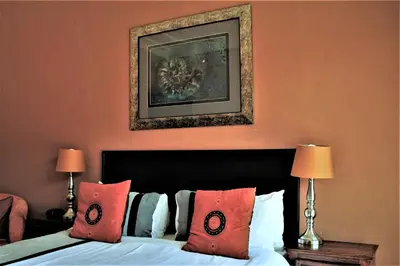 a bedroom with a bed with red pillows and a picture at African Roots Guest House in Polokwane