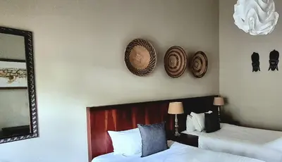 a bedroom with two beds and a mirror and hats on the wall at African Roots Guest House in Polokwane