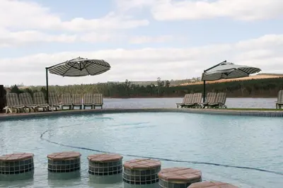 a swimming pool with chairs and umbrellas at Pine Lake Resort in White River