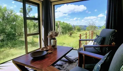 a living room with a table and a large window at Graceland Eco Retreat in Magoebaskloof