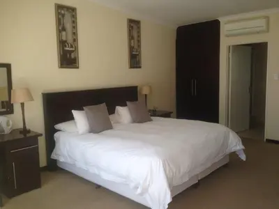 a bedroom with a large bed with white sheets and pillows at The Lazy Grape Guest Lodge & Spa in Benoni