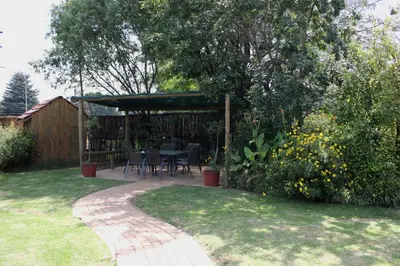 a patio with a table and chairs in a garden at The Lazy Grape Guest Lodge & Spa in Benoni