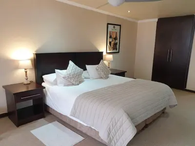 a bedroom with a large white bed with two lamps at The Lazy Grape Guest Lodge & Spa in Benoni