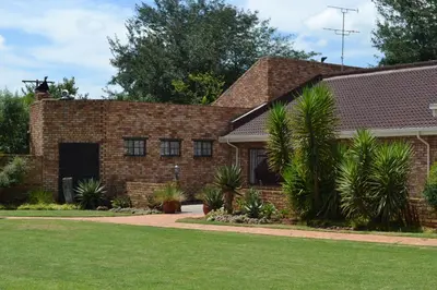 a brick house with palm trees in front of it at The Lazy Grape Guest Lodge & Spa in Benoni