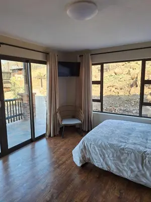 a bedroom with a bed and a chair and sliding glass doors at Dream Of Nature in Bela-Bela