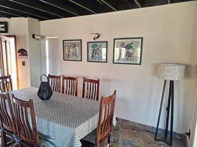 a dining room with a table and chairs and a lamp at Dream Of Nature in Bela-Bela