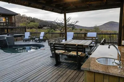a wooden deck with a table and benches next to a pool at Dream Of Nature in Bela-Bela