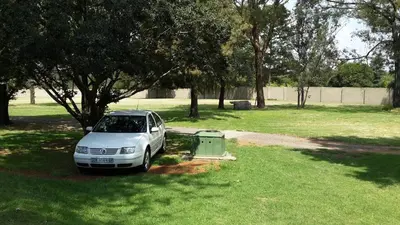 a white car parked in the grass in a field at Anna Boeremeisie Guesthouse in Benoni