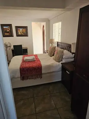 a bedroom with a large bed with a red blanket at TCS on Lynnwood Guesthouse in Pretoria