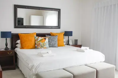 a bedroom with a large white bed with a mirror at TCS on Lynnwood Guesthouse in Pretoria