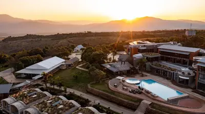 an aerial view of a resort with the sun setting over the mountains at Angels View Hotel in Graskop