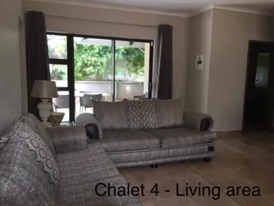 a living room with a couch and a large window at Impala Chalets in Phalaborwa