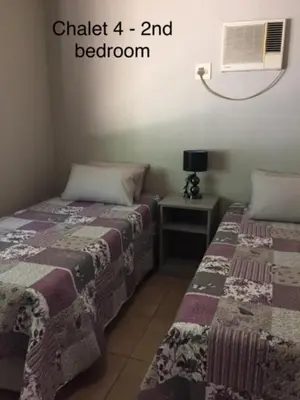 a bedroom with two beds next to a night stand at Impala Chalets in Phalaborwa