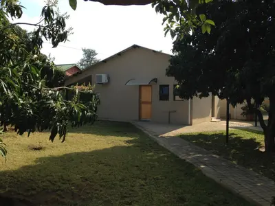 a white building with a door in a yard at Impala Chalets in Phalaborwa