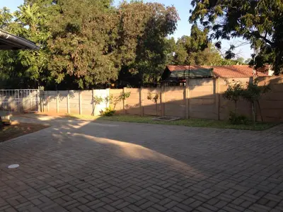 a brick driveway in front of a fence with trees at Impala Chalets in Phalaborwa