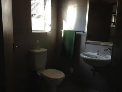 a bathroom with a white toilet and a sink at Impala Chalets in Phalaborwa