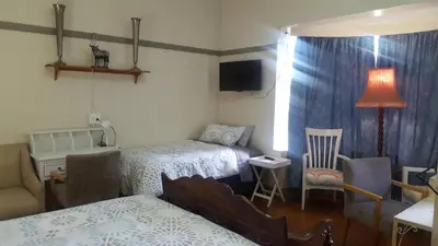 a bedroom with two beds and a table and chairs at Pretoria Inn in Pretoria