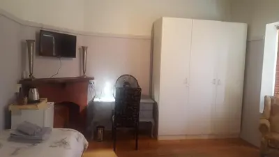 a living room with a bed and a tv on the wall at Pretoria Inn in Pretoria