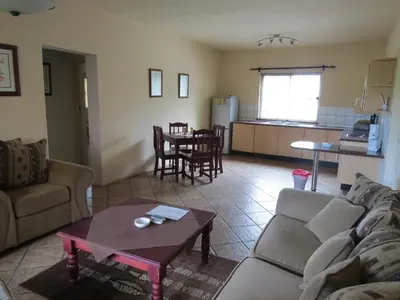 a living room with a couch and a table and a kitchen at Crocodile Lodge cc in Midrand