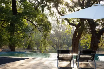 two chairs and an umbrella next to a swimming pool at Southern Sands Eco Lodge in Hoedspruit