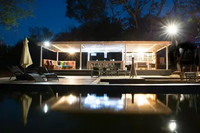 a building with a pool at night with lights at Southern Sands Eco Lodge in Hoedspruit