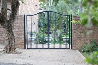 a black metal gate in front of a brick wall at 513 on Mulberry in Pretoria
