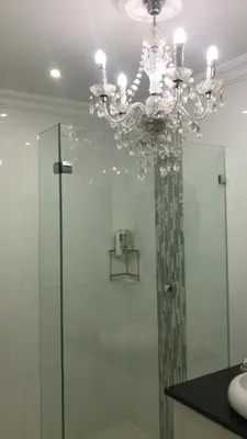 a bathroom with a glass shower with a chandelier at 513 on Mulberry in Pretoria