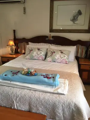 a bed with a blue blanket and flowers on it at Sunninghill Sojourn in Kyalami