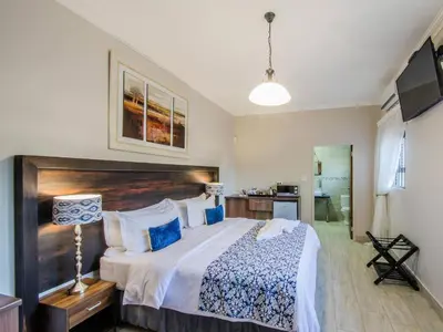 a bedroom with a large bed with a wooden headboard at Three Olives Guesthouse in Centurion