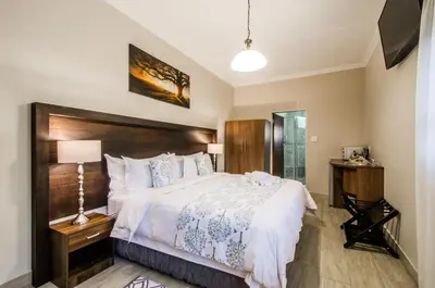 a bedroom with a large bed with a wooden headboard at Three Olives Guesthouse in Centurion