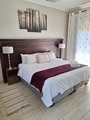 a bedroom with a large bed with a wooden headboard at Three Olives Guesthouse in Centurion