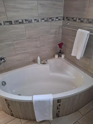 a white bath tub in a bathroom with towels at Three Olives Guesthouse in Centurion