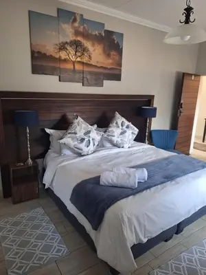 a bedroom with a large bed with two paintings on the wall at Three Olives Guesthouse in Centurion