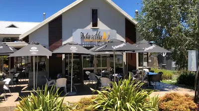 a restaurant with tables and umbrellas in front of a building at Stay@67 Apartments - Dullstroom in Dullstroom