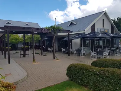 a patio with chairs and umbrellas in front of a building at Stay@67 Apartments - Dullstroom in Dullstroom