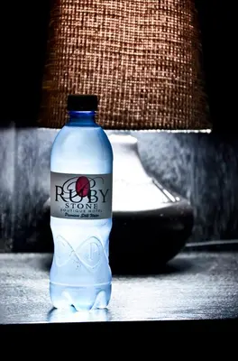 a bottle of water sitting on a table next to a lamp at Ruby Stone Boutique Hotel in Polokwane