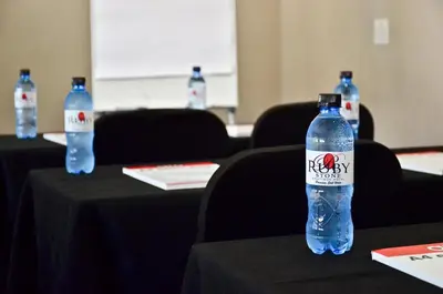two bottles of water sitting on tables in a room at Ruby Stone Boutique Hotel in Polokwane