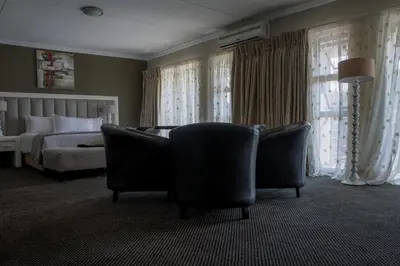 a hotel room with two chairs and a bed at Ruby Stone Boutique Hotel in Polokwane