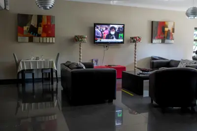 a living room with couches and a table and a tv at Ruby Stone Boutique Hotel in Polokwane