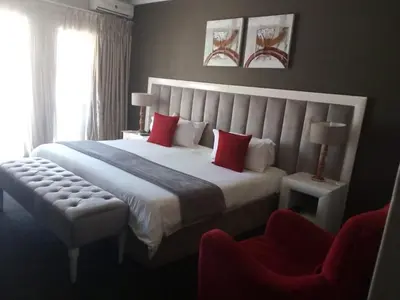 a bedroom with a large white bed with red pillows at Ruby Stone Boutique Hotel in Polokwane