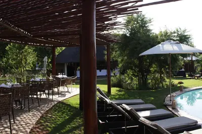a patio with tables and chairs and an umbrella at The Blades in Pretoria
