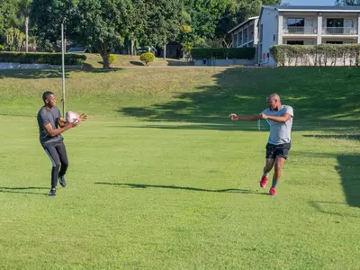two men playing with a soccer ball on a field at ANEW Resort White River Mbombela in White River