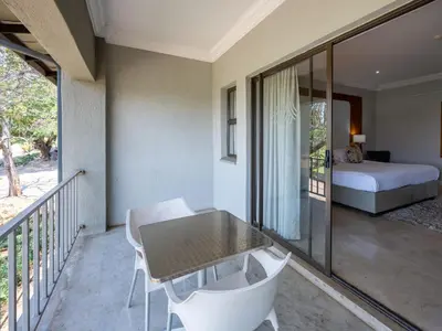 a room with a balcony with a table and chairs at ANEW Resort White River Mbombela in White River
