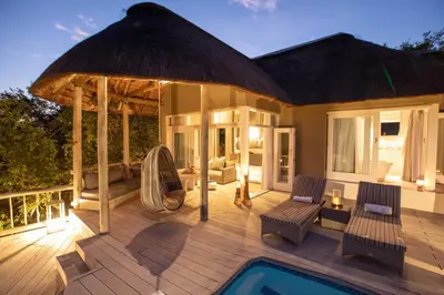 a villa with a swimming pool and a deck with a umbrella at Clifftop Exclusive Safari Hideaway in Welgevonden Game Reserve