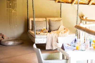 a swing in a room with a table and chairs at Clifftop Exclusive Safari Hideaway in Welgevonden Game Reserve