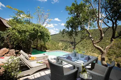 a patio with a table and chairs and a pool at Clifftop Exclusive Safari Hideaway in Welgevonden Game Reserve