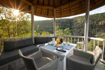 a table and chairs on a porch with a view at Clifftop Exclusive Safari Hideaway in Welgevonden Game Reserve