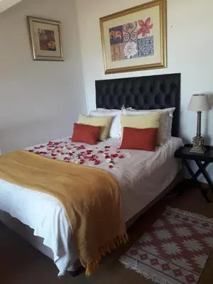 a bedroom with a large bed with red pillows at Hartbeespoortdam Lodge in Hartbeespoort