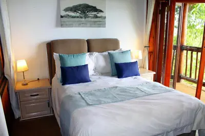 a bedroom with a large bed with blue pillows at Hartbeespoortdam Lodge in Hartbeespoort